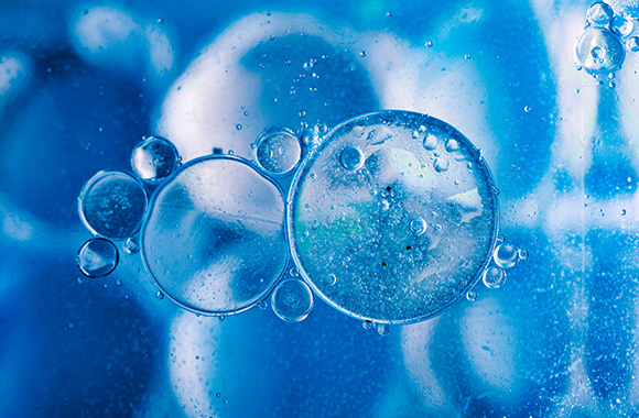 Macro shot of water oil emulsion over colored background